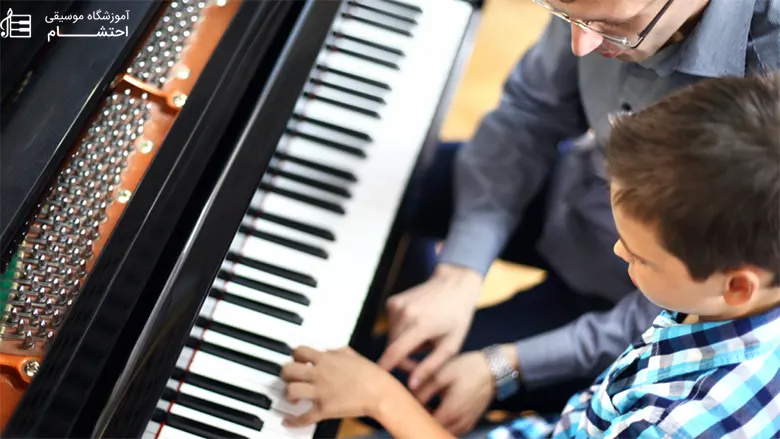 a boy learning piano from a man
