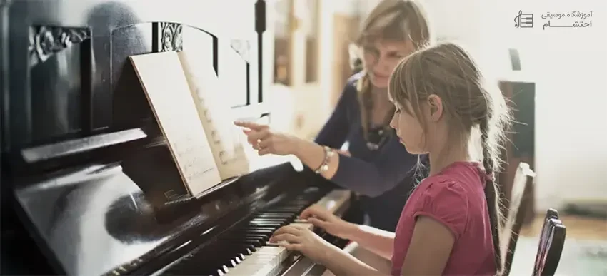 a little girl is learning piano with a women