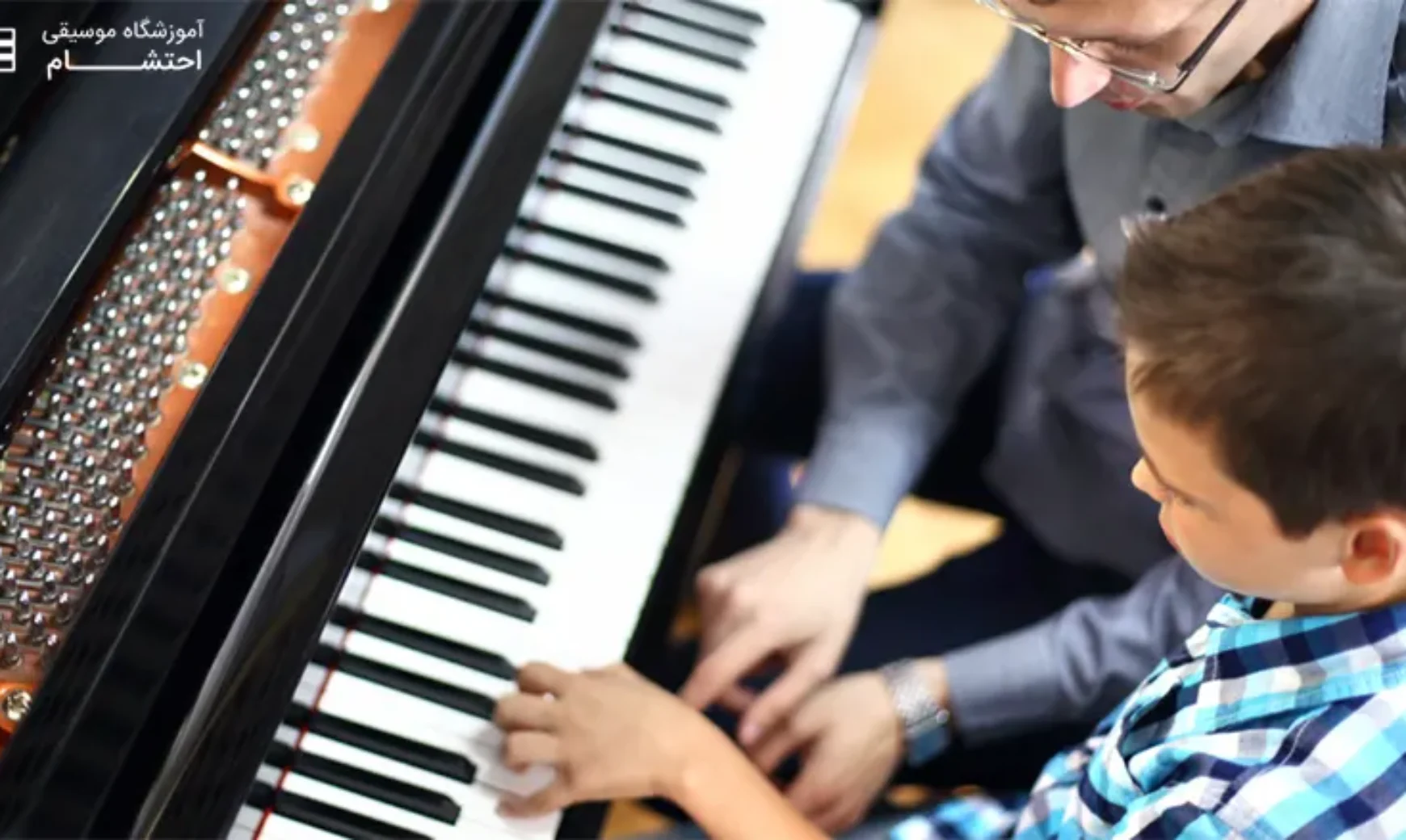 a boy learning piano from a man