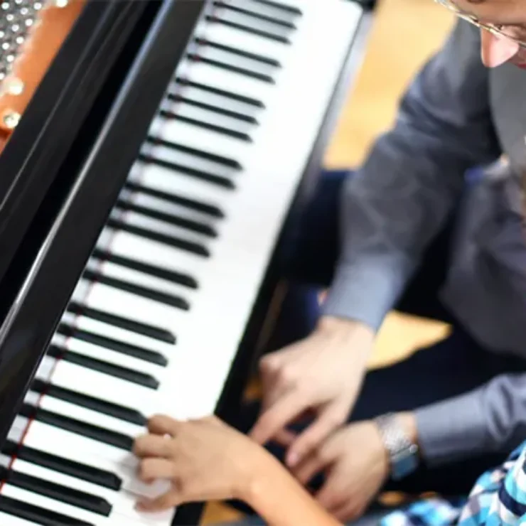 a boy learning piano from a man