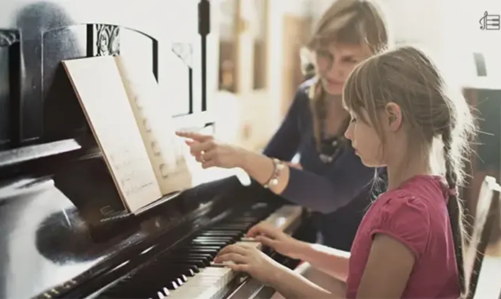 a little girl is learning piano with a women